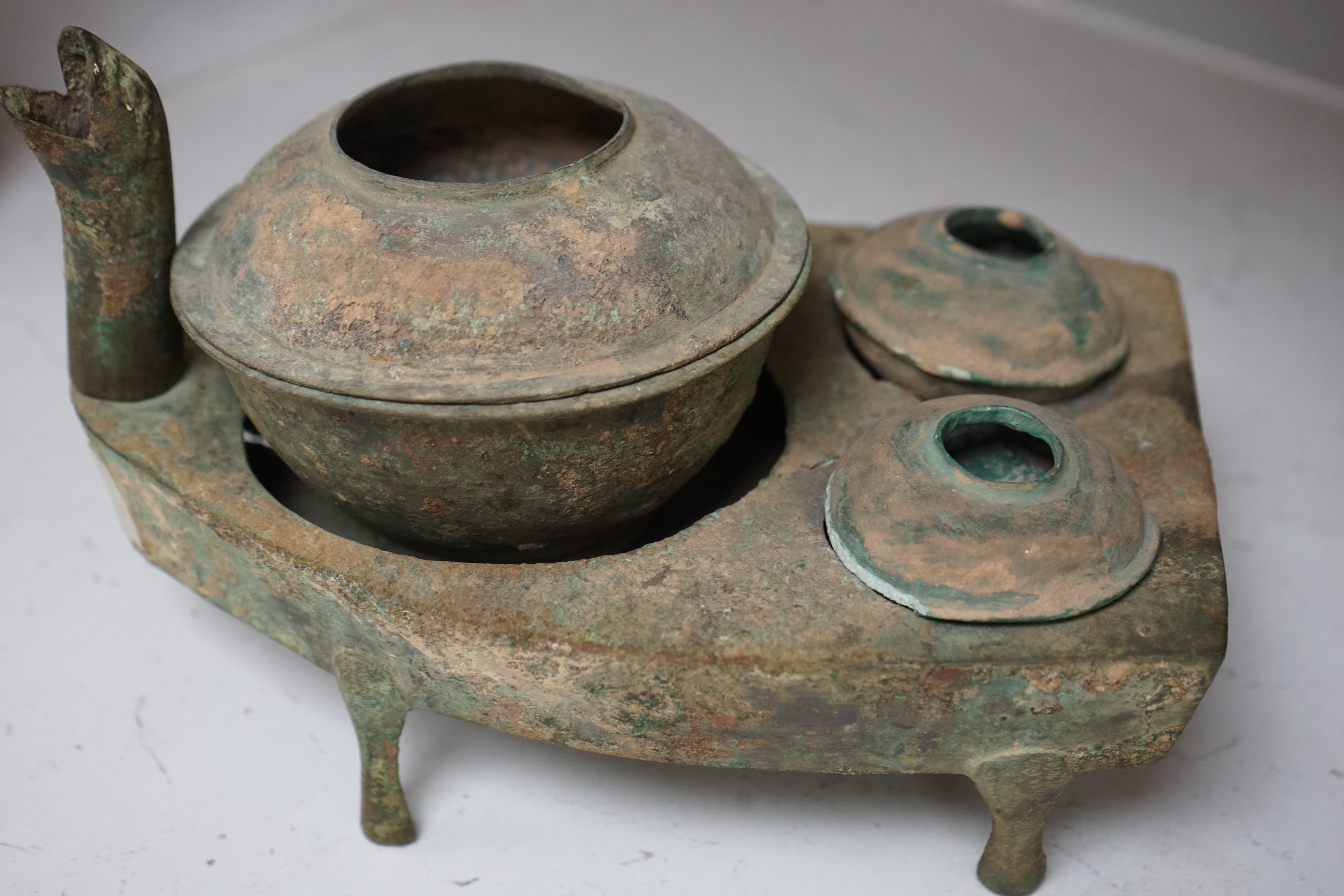 Four Chinese bronze zoomorphic stoves, Han Dynasty, 22cm, together with a Han Dynasty bronze brazier and vessels, width 22.5cm, (5). Condition - poor to fair.